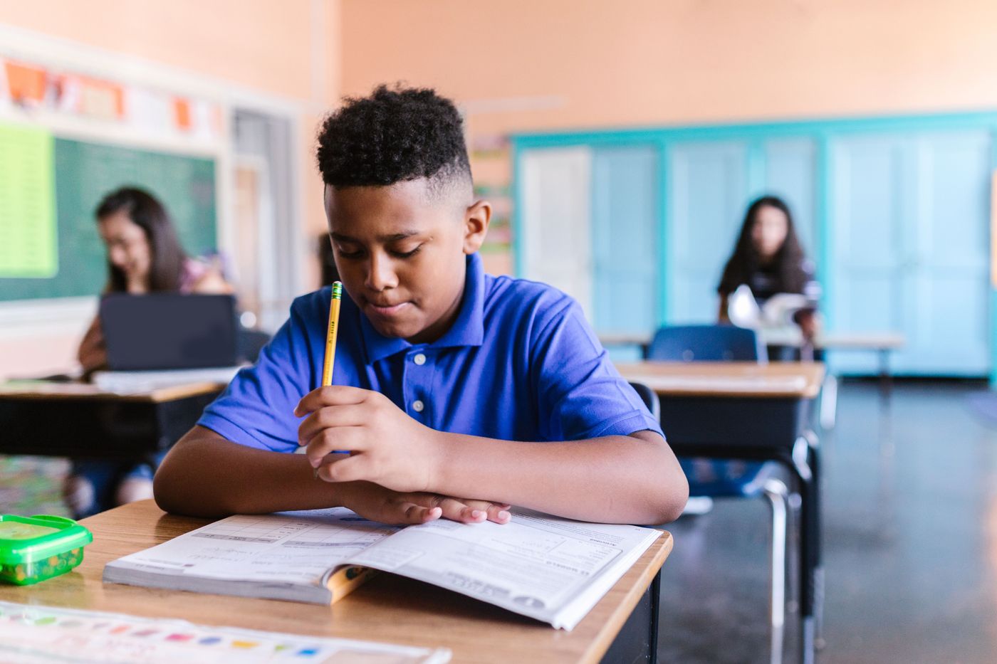 An upper-elementary student working through a workbook at a classroom desk
