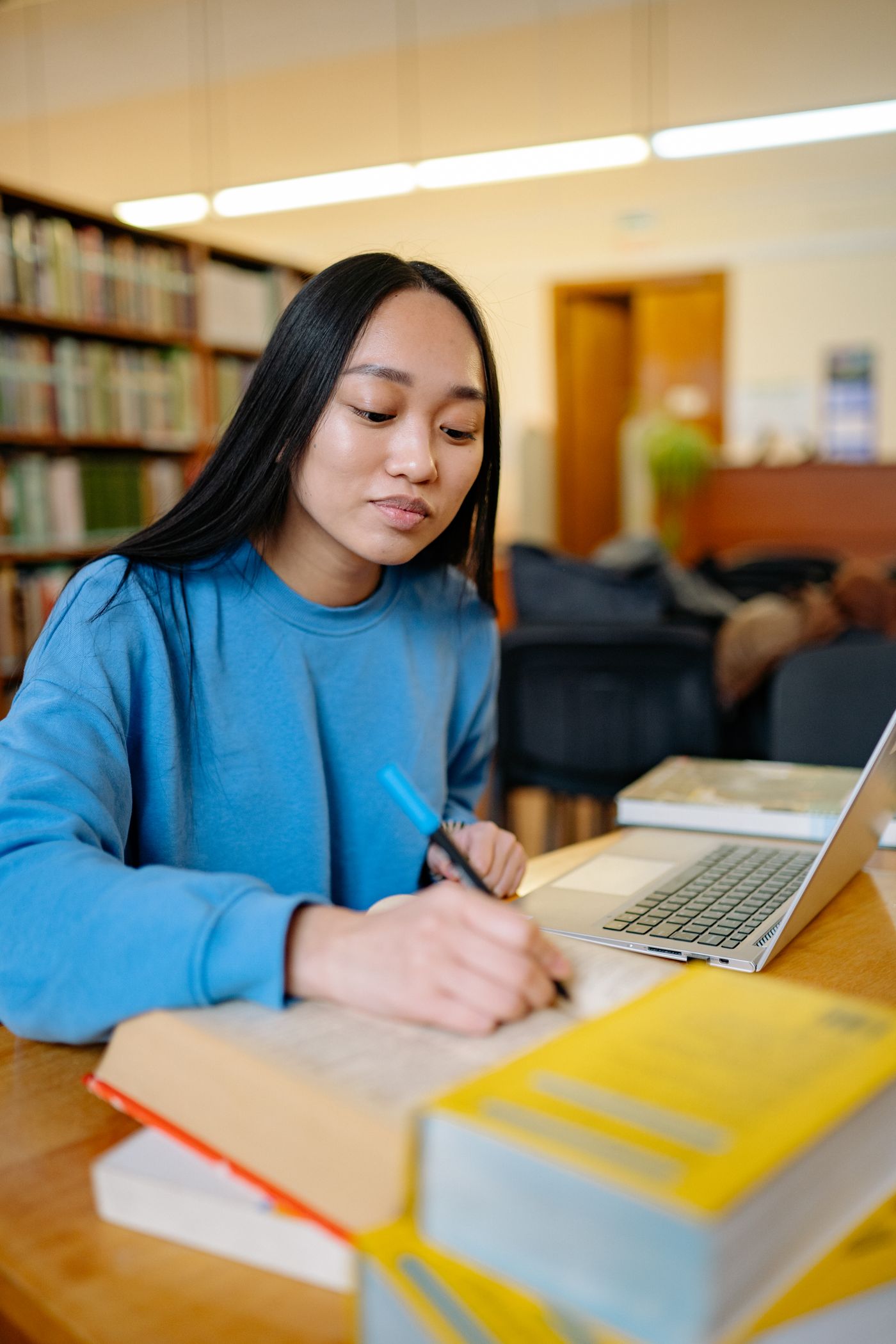 A student writing notes in front of library shelves