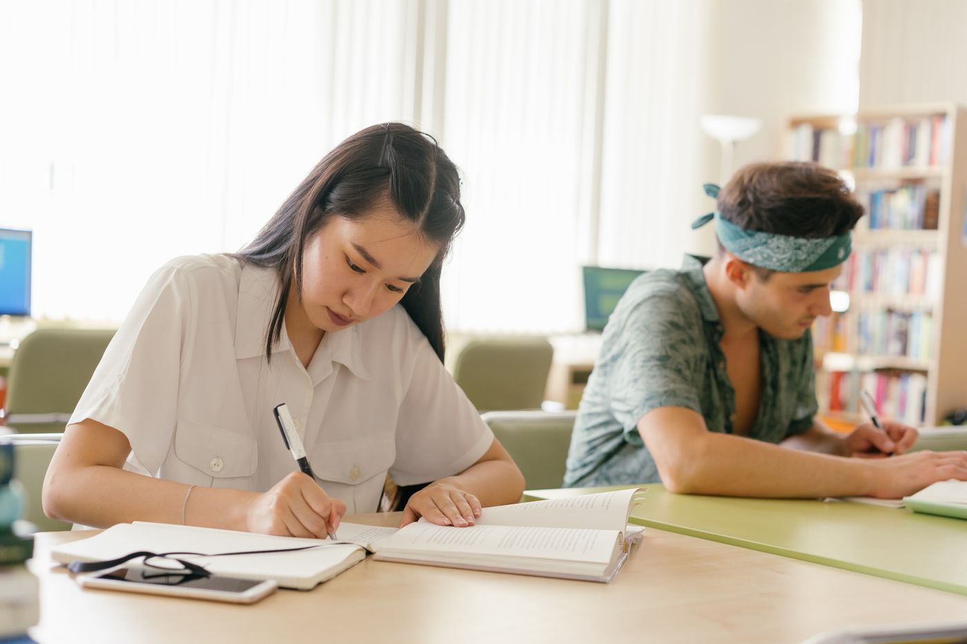 Two students studying side by side in a library