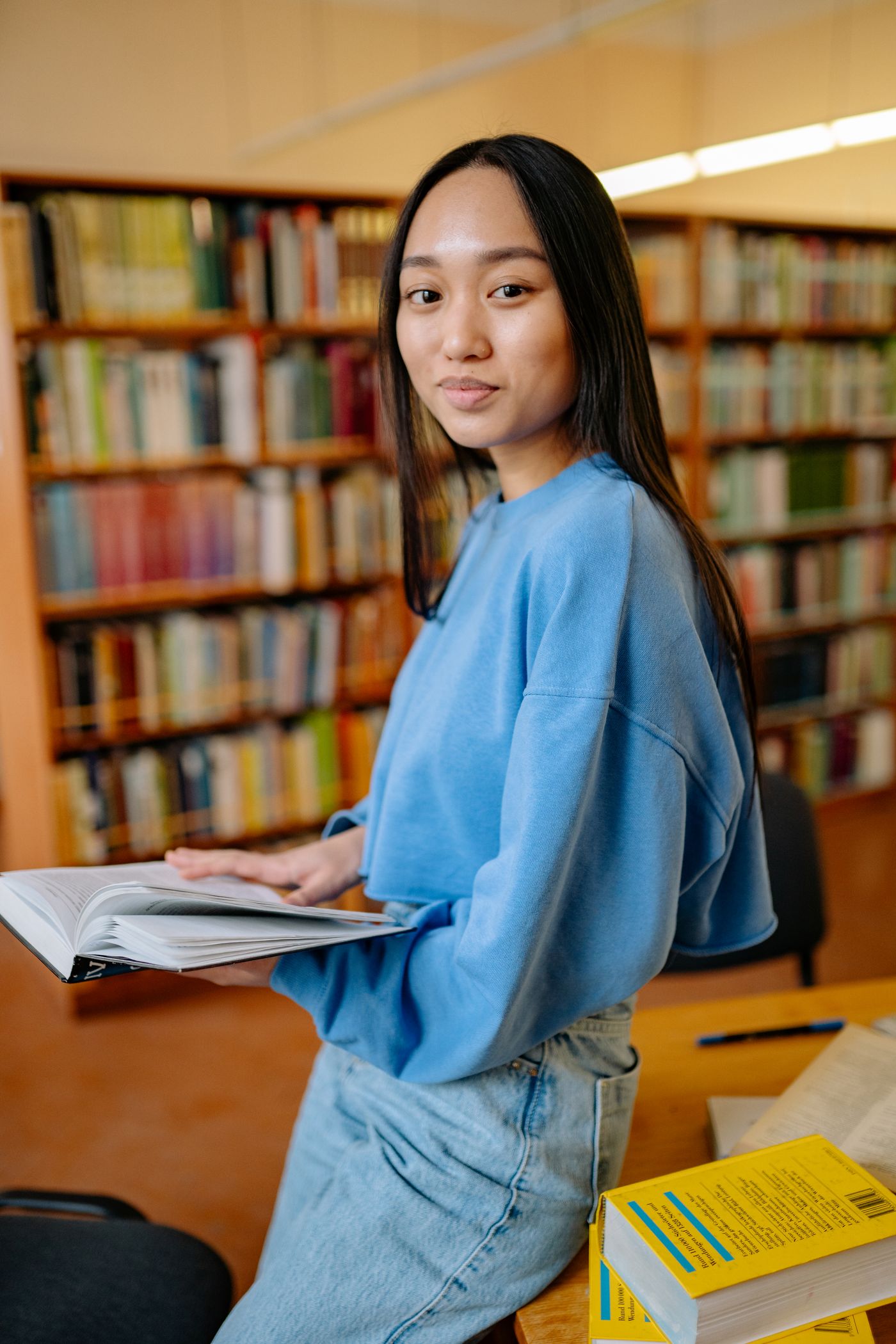 A student paging through a book in a library