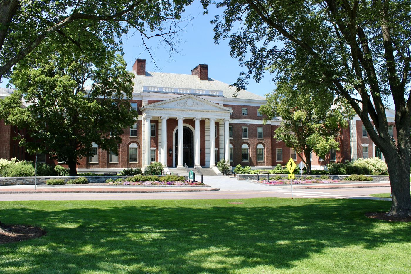 A red-brick school building with a white columned portico and a lawn