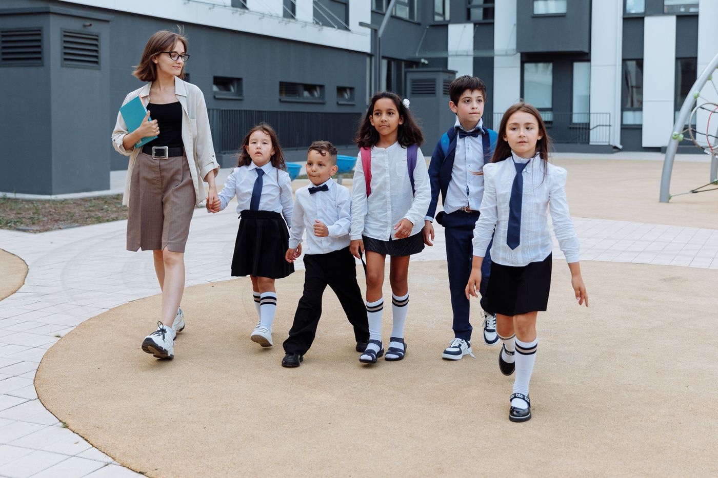Students in matching school uniforms walking out together across the schoolyard